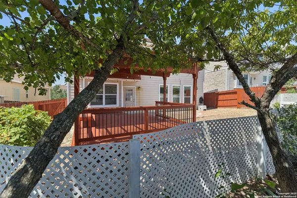 a view of backyard with large trees and wooden fence