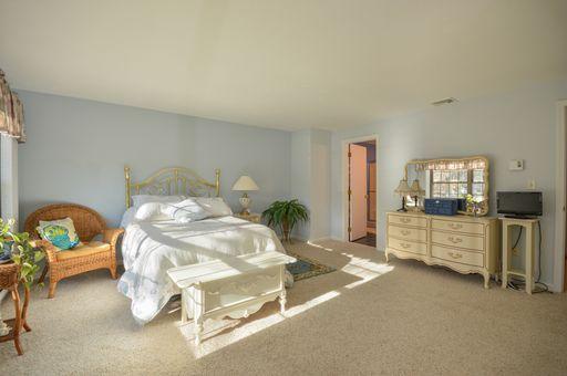195 Falmouth Road, Unit 14C Mashpee, MA 02649 - Photo 16 of 27 a bedroom with a bed and a chair