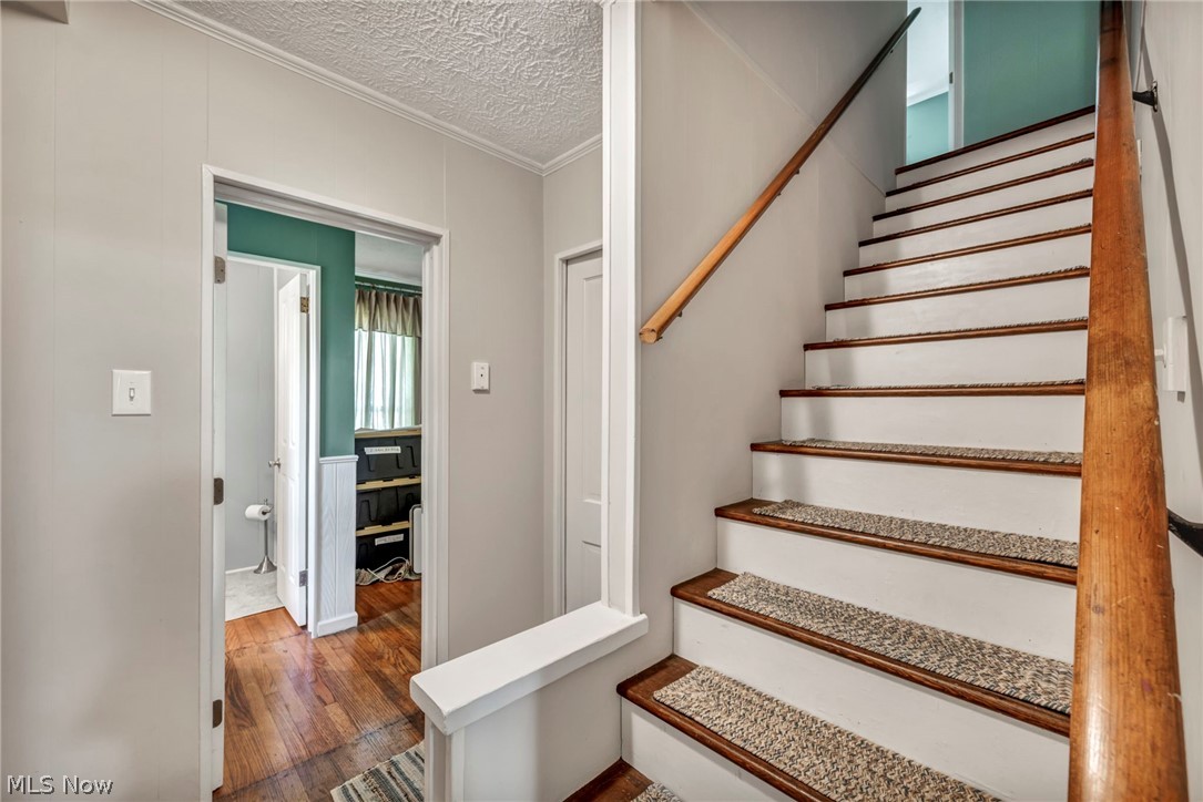 6144 Ridge Road Wadsworth, OH 44281 - Photo 25 of 48 Stairs featuring dark hardwood / wood-style floors, a textured ceiling, and ornamental molding