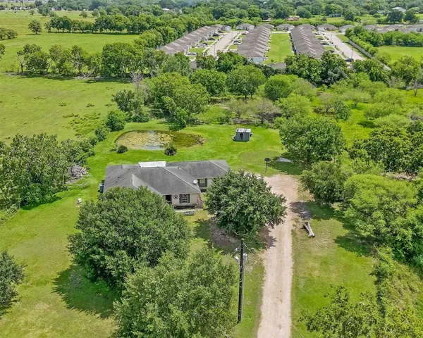 an aerial view of a houses with outdoor space and trees all around