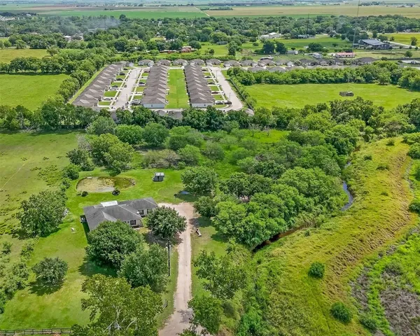 an aerial view of a residential houses with outdoor space and trees
