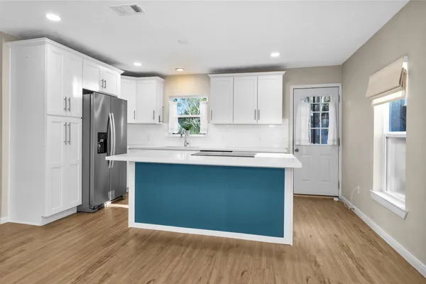 a kitchen with stainless steel appliances granite countertop a refrigerator and a sink with wooden floors