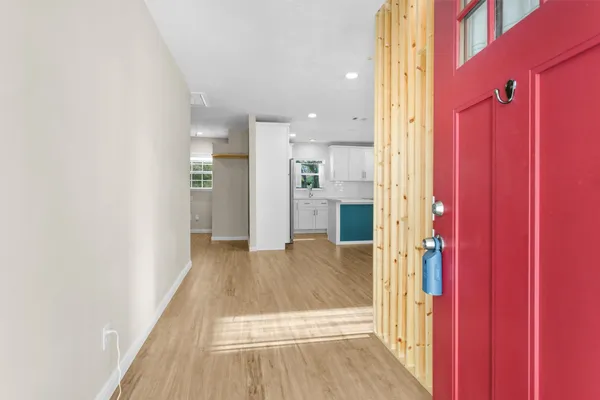 a view of a hallway with wooden floor and a bathroom