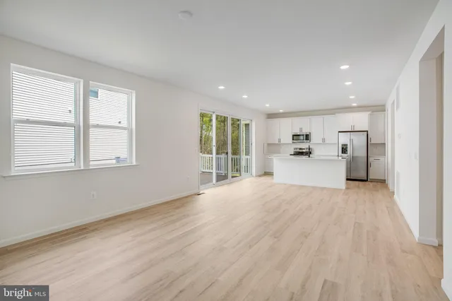 a view of kitchen with stainless steel appliances granite countertop a stove a refrigerator a sink and a large window with wooden floor
