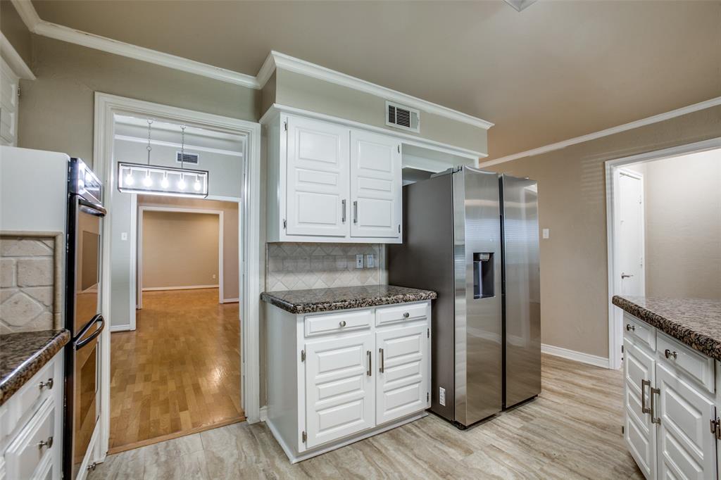 2700 Quail Ridge Drive Carrollton, TX 75006 - Photo 10 of 30 Kitchen featuring white cabinets, backsplash, ornamental molding, appliances with stainless steel finishes, and light wood-type flooring