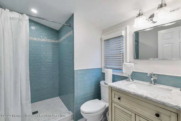 a bathroom with a granite countertop sink toilet a mirror and shower