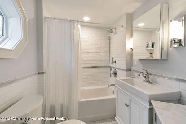 a bathroom with a bathtub shower sink vanity and toilet