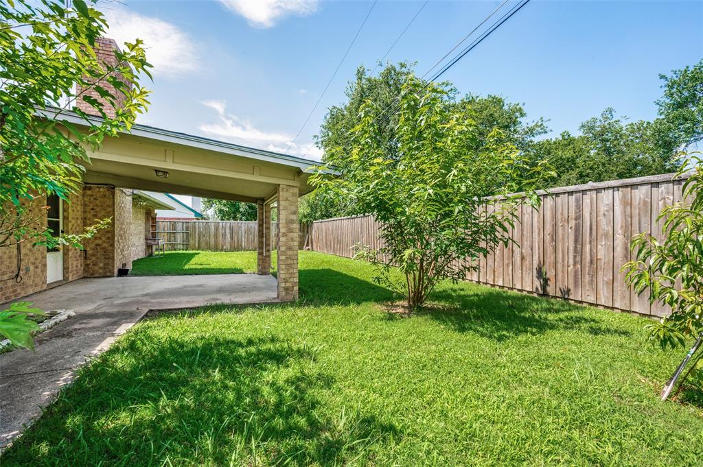 508 South Pedigo Street Pilot Point, TX 76258 - Photo 25 of 26 Spacious backyard featuring a covered carport, full privacy fencing, mature landscaping, and a brick exterior
