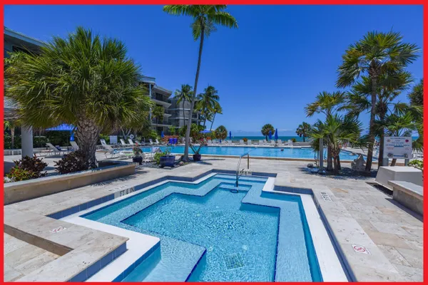 a view of a swimming pool with lounge chair and palm trees