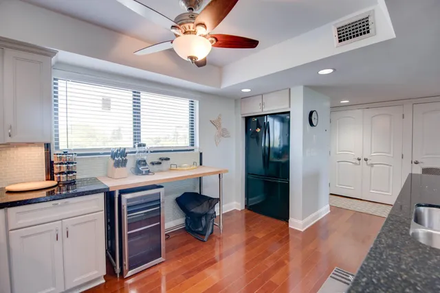 a kitchen with stainless steel appliances granite countertop a refrigerator a sink dishwasher a stove and white countertops with wooden floor