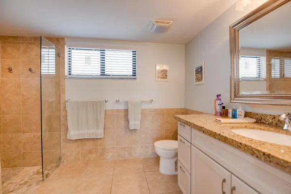 a bathroom with a granite countertop sink a toilet a mirror and bathtub
