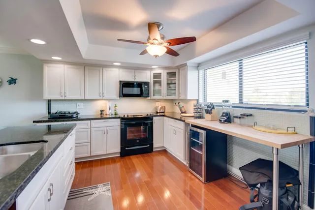 a kitchen with kitchen island granite countertop a sink cabinets stainless steel appliances and a large window