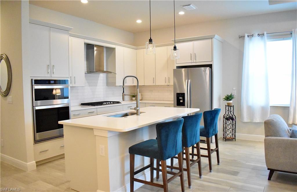 9175 Cayman Drive Naples, FL 34114 - Photo 13 of 31 a kitchen with stainless steel appliances a table chairs refrigerator and microwave