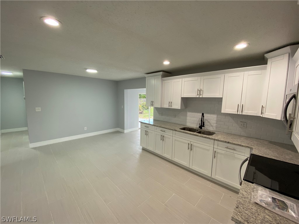 2316 Lotus Road Fort Myers, FL 33905 - Photo 13 of 35 a large kitchen with granite countertop a sink and white cabinets