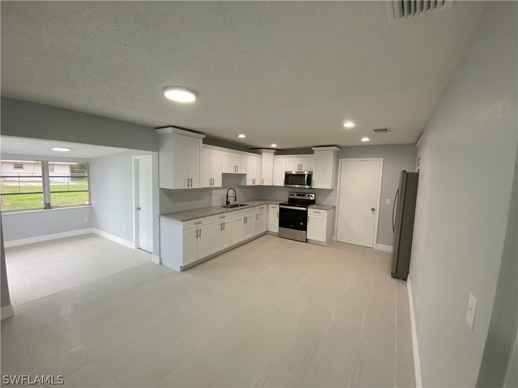 2316 Lotus Road Fort Myers, FL 33905 - Photo 9 of 35 a large kitchen with stainless steel appliances granite countertop a refrigerator and a sink