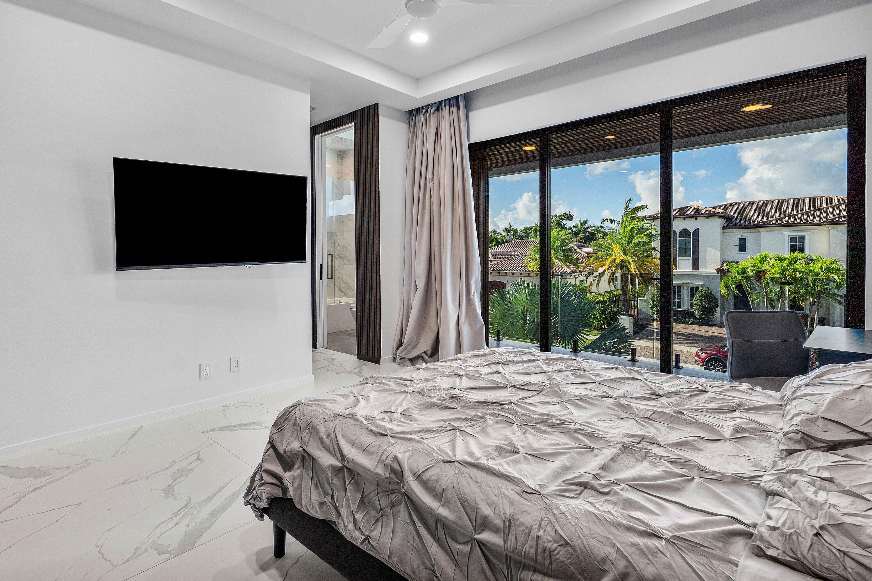 245 Northeast 6th Court Boca Raton, FL 33432 - Photo 21 of 84 a bedroom with a large bed and a flat screen tv