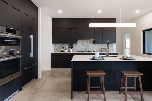 a kitchen with kitchen island granite countertop a sink and a refrigerator