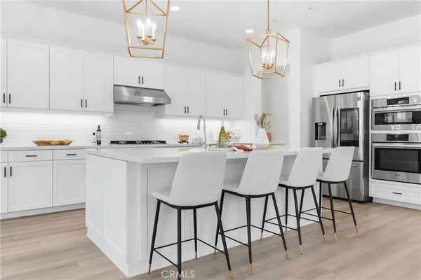 a kitchen with stainless steel appliances a dining table chairs refrigerator and cabinets