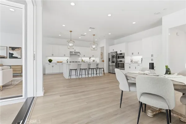 a dining room with wooden floor a chandelier a glass table and chairs