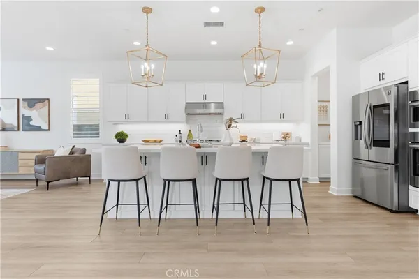 a kitchen with stainless steel appliances kitchen island granite countertop a dining table chairs sink and cabinets