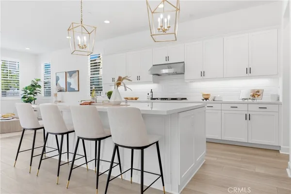 a kitchen with stainless steel appliances kitchen island granite countertop a table chairs in it and white cabinets