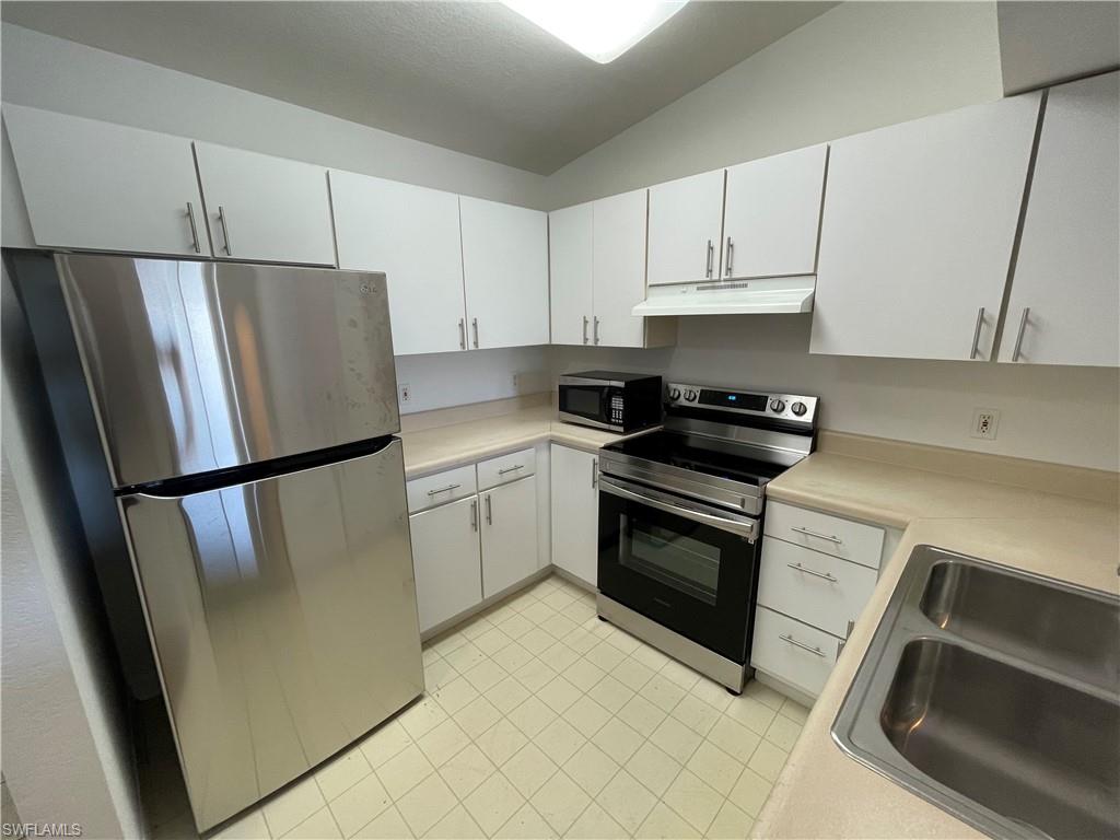 a kitchen with a refrigerator sink and cabinets