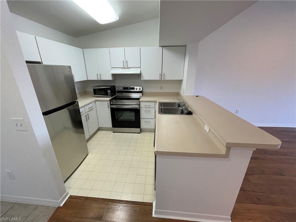 8234 Key Royal Circle, Unit 533 Naples, FL 34119 - Photo 2 of 24 a kitchen with a sink a refrigerator a stove and white cabinets