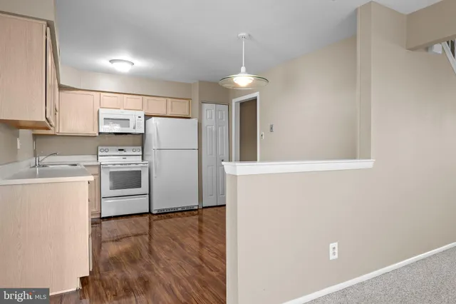 a kitchen with a refrigerator a stove top oven a sink and dishwasher with wooden floor