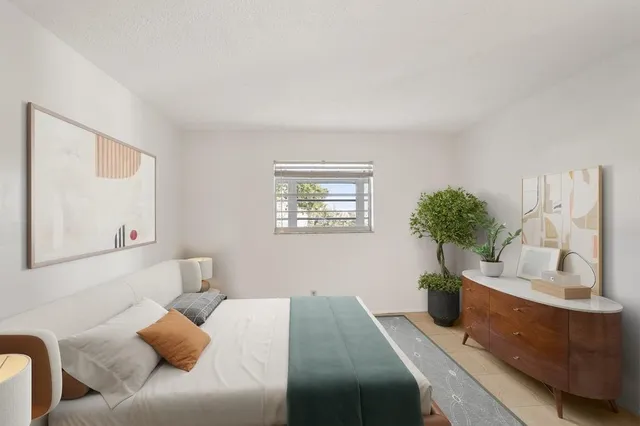 a bedroom with a bed and a potted plant
