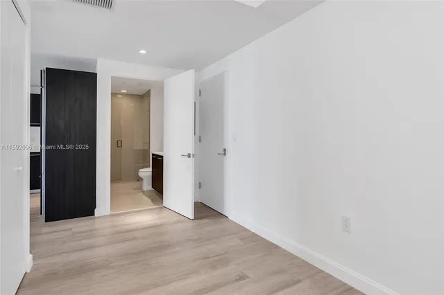 a view of a hallway with wooden floor and closet area