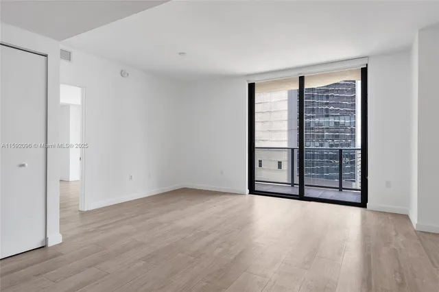 a view of an empty room with wooden floor and a window