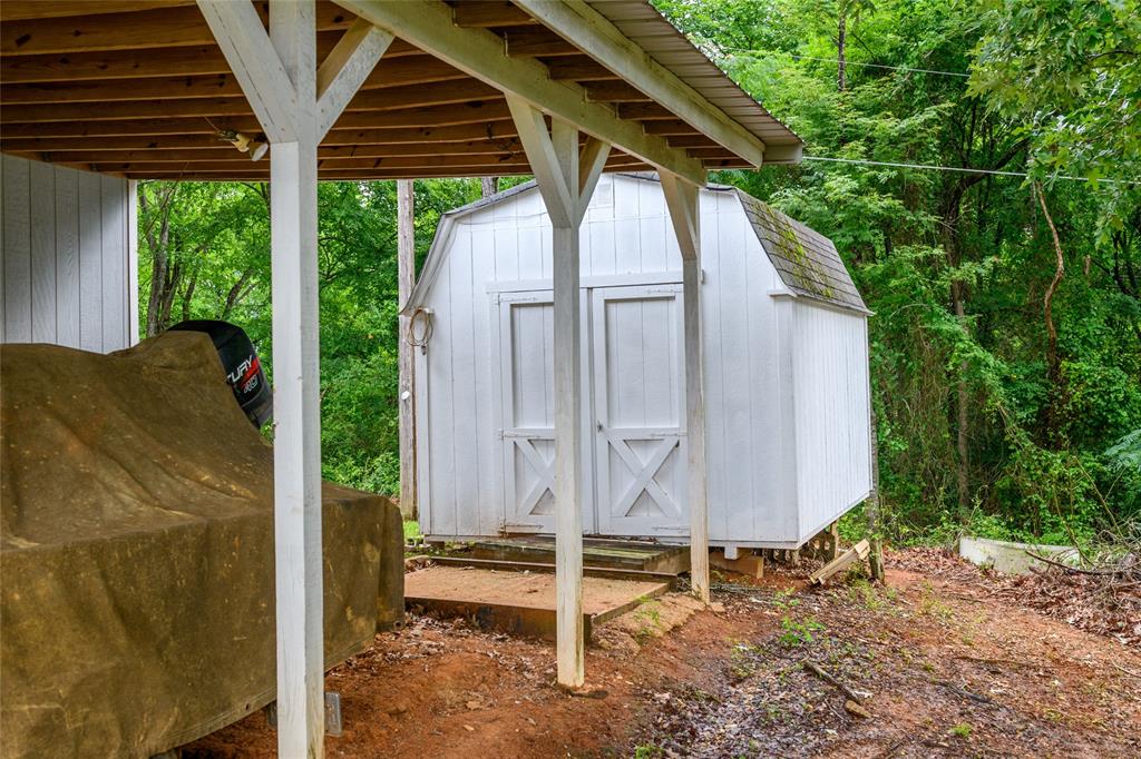 122 Grice Road Ringgold, LA 71068 - Photo 26 of 26 White wooden shed with a gable roof and dual X-brace doors, positioned on a raised foundation