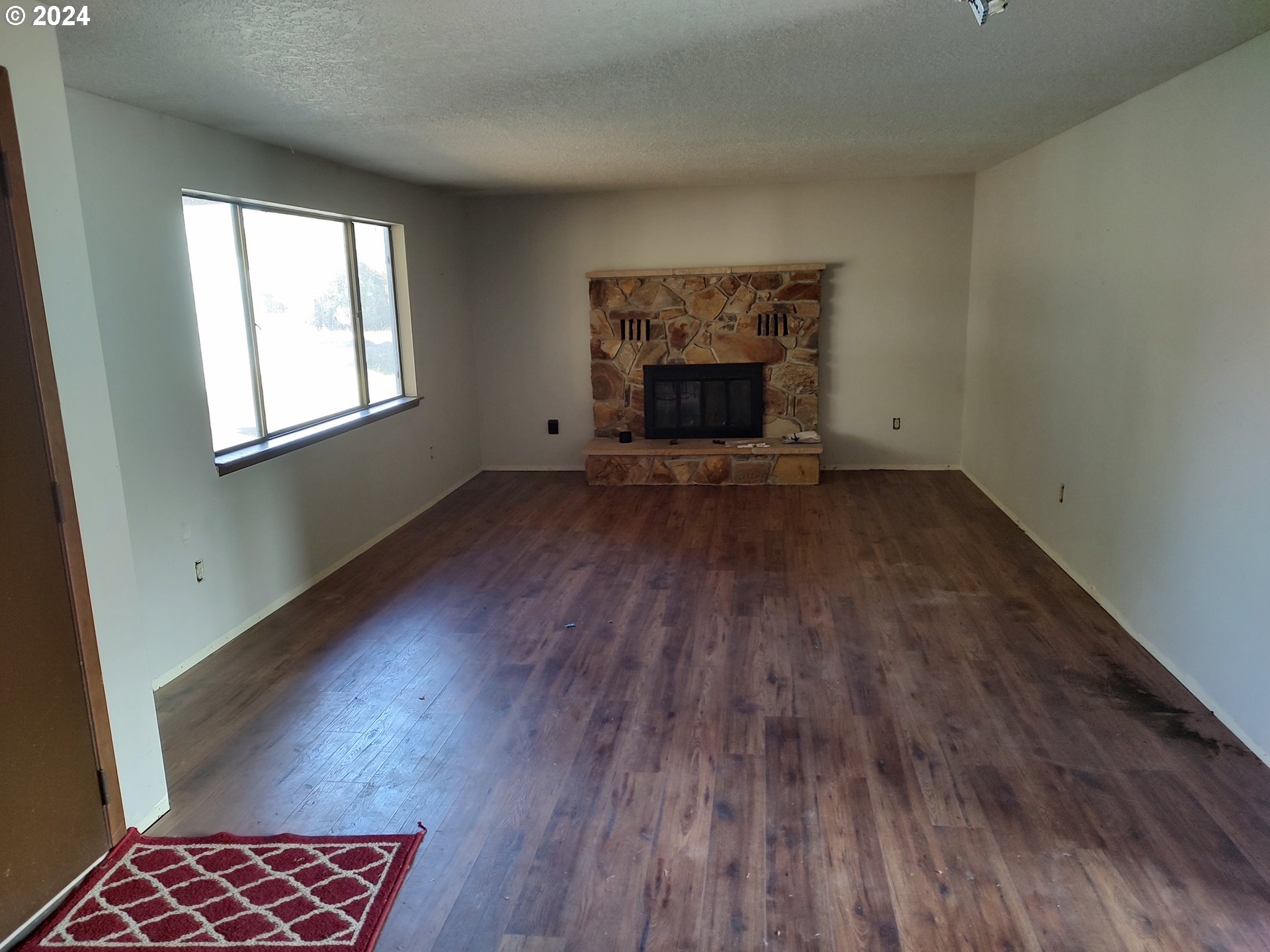 75657 Upper Diamond Lane Wallowa, OR 97885 - Photo 13 of 21 an empty room with wooden floor a fireplace and windows