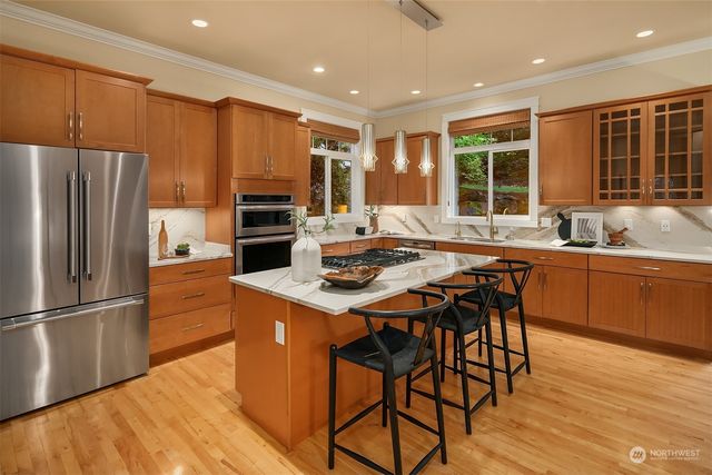 a kitchen with stainless steel appliances granite countertop a stove a refrigerator a sink a dining table and chairs