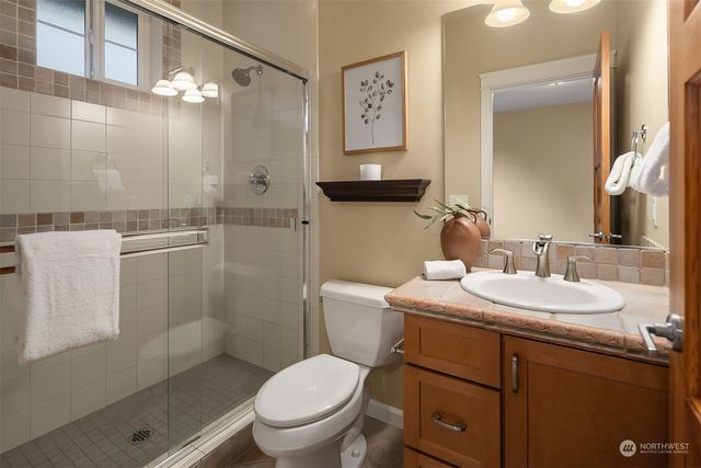 a bathroom with a toilet sink vanity granite and shower