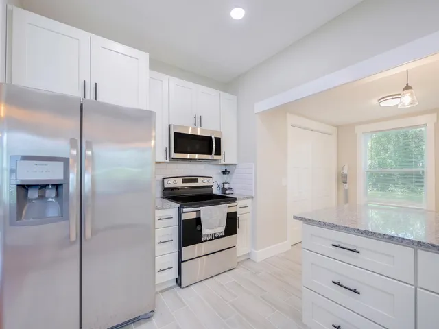 a kitchen with white cabinets stainless steel appliances and a window