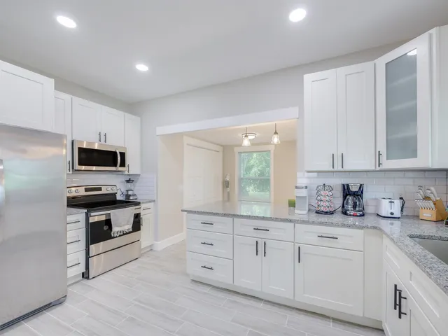 a kitchen with granite countertop white cabinets and stainless steel appliances