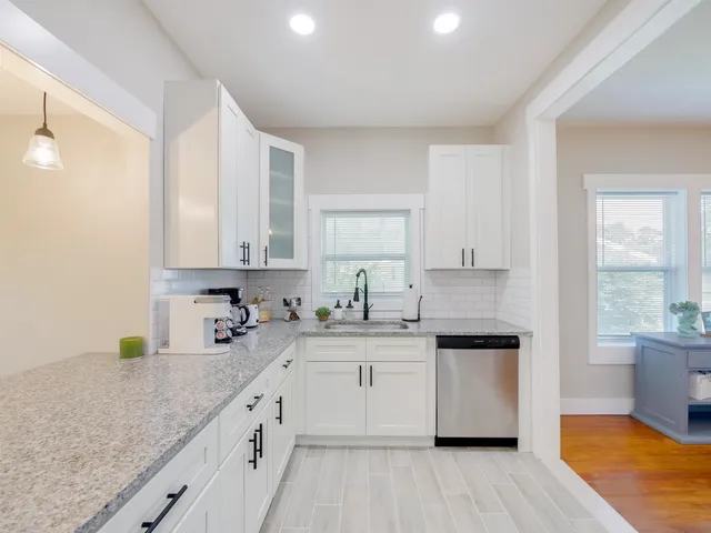 a kitchen with a sink dishwasher a stove and white cabinets with wooden floor