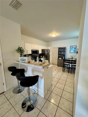 a kitchen with stainless steel appliances kitchen island granite countertop a sink a stove a dining table and chairs