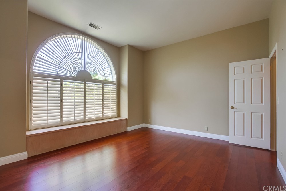 3036 Southwind Lane Vista, CA 92084 - Photo 31 of 45 an empty room with wooden floor exposed radiator and windows