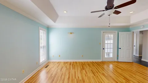 a view of empty room with wooden floor and fan