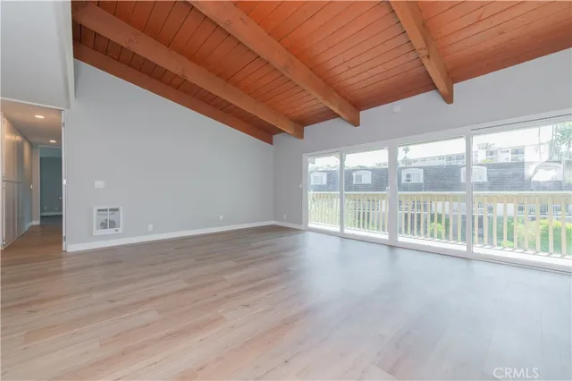 a view of an empty room with wooden floor and a floor to ceiling window