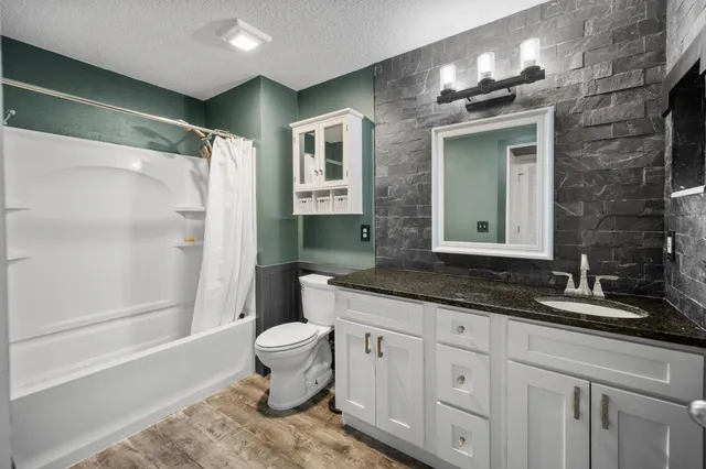 a spacious bathroom with a granite countertop sink toilet and shower
