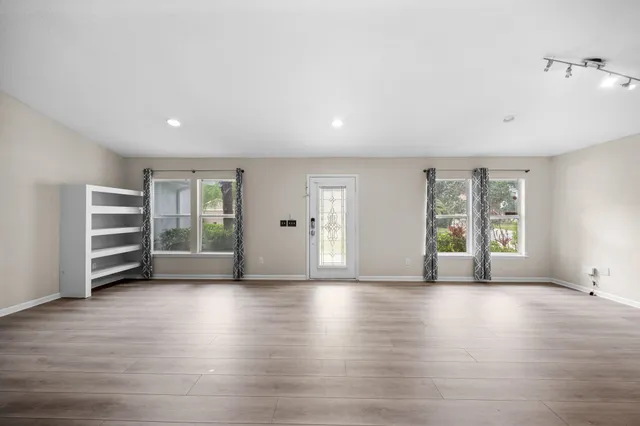 a view of an empty room with a window and wooden floor