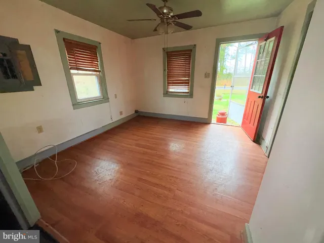 a view of an empty room with a window and wooden floor