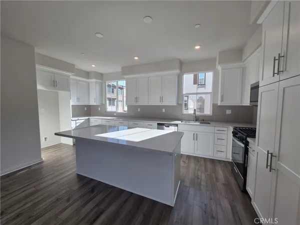 a kitchen with kitchen island granite countertop a sink cabinets and wooden floor