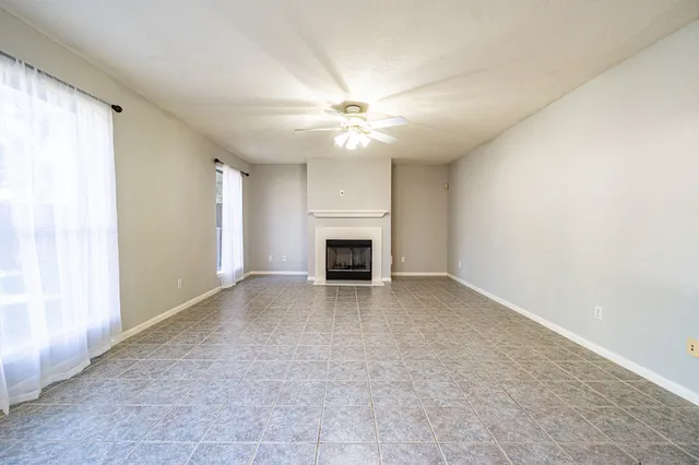 an empty room with a fireplace and a ceiling fan