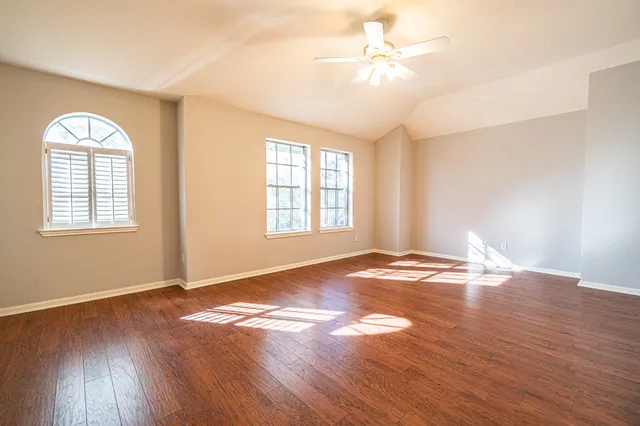 a view of empty room with wooden floor and fan