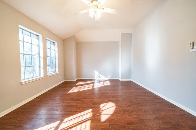 a view of empty room with wooden floor and fan