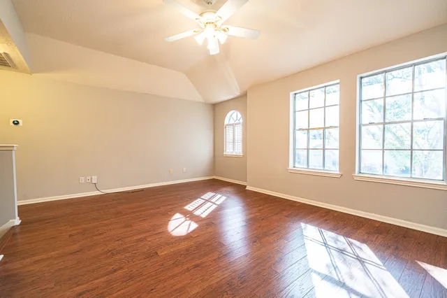 a view of an empty room with wooden floor and a window
